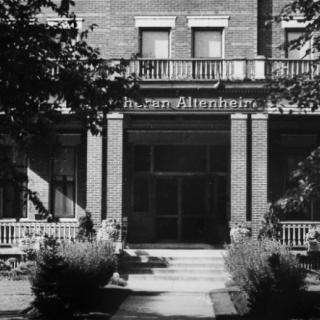 The entrance of a historic building with prominent columns, captured in black and white.