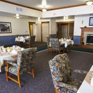 A cozy dining room with tables set for guests and a warm fireplace.