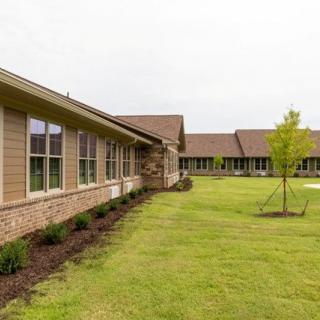 A view of a modern building with large windows and a well-maintained lawn.