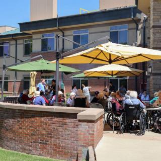 A group of people enjoying an outdoor gathering on a patio with umbrellas.