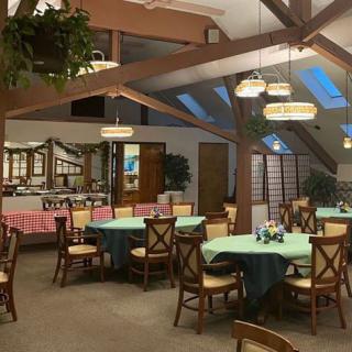 A cozy restaurant interior with several tables set for dining and a buffet area in the background.