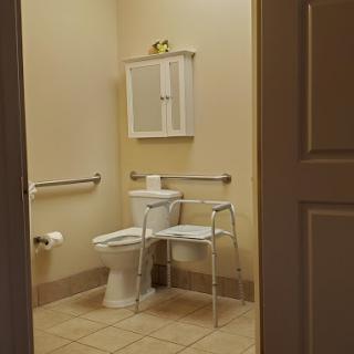 A view of a clean, accessible bathroom featuring a toilet and support bars.