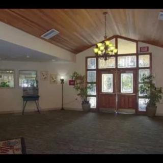 A spacious lobby area featuring a chandelier, large windows, and double wooden doors.