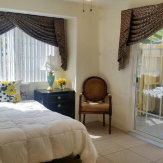 A cozy bedroom featuring a bed with white bedding, elegant curtains, and a comfortable chair by the window.