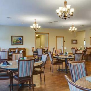 A spacious dining room with multiple tables and chairs, decorated with chandeliers.