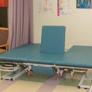 A physical therapy room featuring a treatment bed with an adjustable backrest.