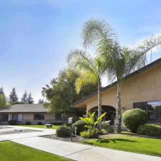 A suburban home with palm trees and well-maintained landscaping on a sunny day.