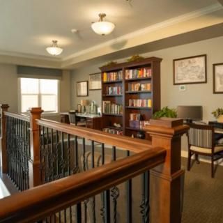 A cozy study area with a bookshelf and desk, enhanced by warm lighting and wooden decor.