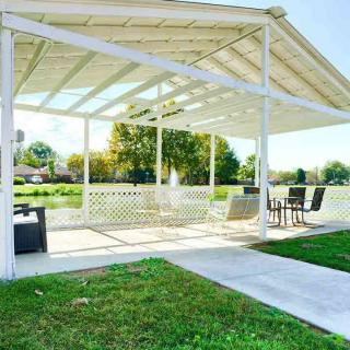 A beautiful outdoor gazebo with patio furniture, set against a lush green lawn on a sunny day.