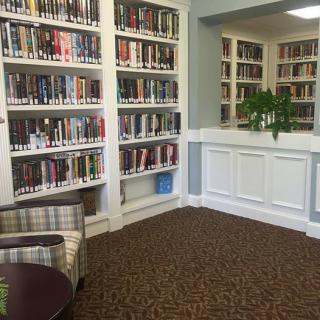 A cozy library corner with bookshelves filled with books and a comfortable chair.