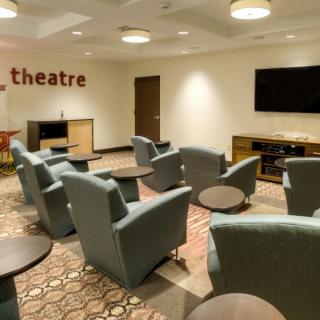 A cozy theater room with comfortable armchairs and a large television on the wall.