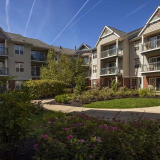 A modern apartment complex with well-maintained gardens and pathways under a clear blue sky.