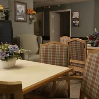A cozy dining area with a central table surrounded by plaid-upholstered chairs and floral decor.