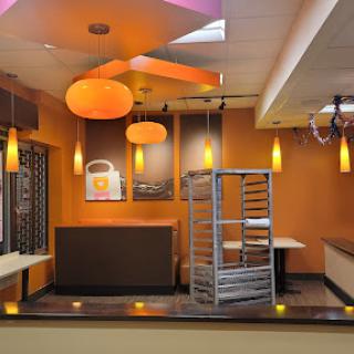 A modern restaurant interior featuring warm orange tones and contemporary lighting.