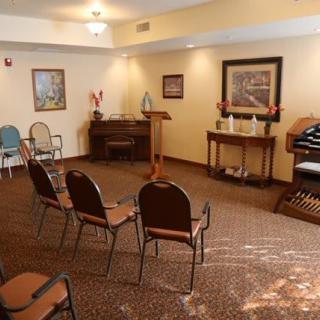 A cozy room with arranged chairs, a piano, and an organ.