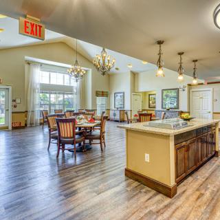 A spacious and modern kitchen with an open dining area, featuring chandeliers and wood flooring.