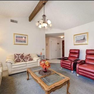 A cozy living room with a sofa, recliner chairs, and a decorative coffee table under a chandelier.