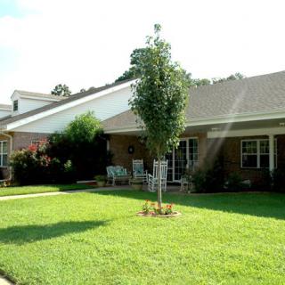 A residential house with a well-maintained lawn and trees on a sunny day.