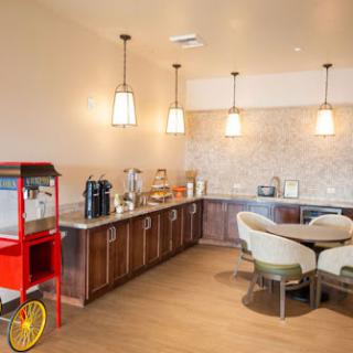 A contemporary kitchen and snack area featuring a coffee machine, popcorn machine, and cozy seating.