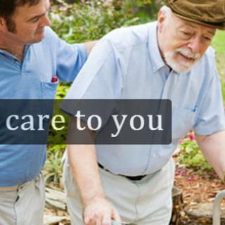 A caregiver assisting an elderly man outdoors.