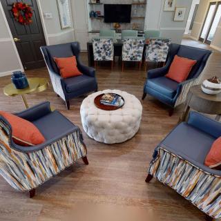 A cozy living room setup with four blue and patterned chairs arranged around a round coffee table.