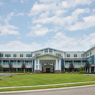 A modern residential building with a well-maintained lawn under a partly cloudy sky.