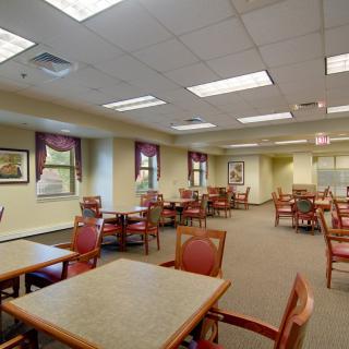 An empty dining area with tables and chairs arranged neatly under bright lighting.