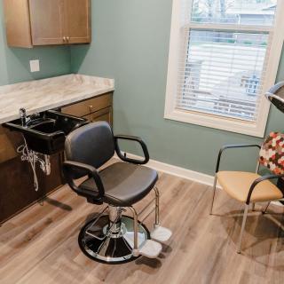 A clean and modern hair salon setup with a salon chair, sink, and window.