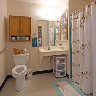 A clean and organized bathroom with a sink, toilet, shower curtain, and storage cabinet.