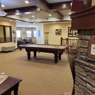 A cozy game room featuring a pool table, comfortable seating, and warm lighting.
