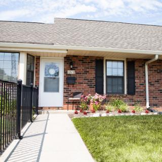 A brick residential house with a small garden in the front yard.
