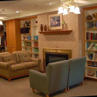 A cozy living room with seating, a fireplace, and bookshelves filled with books.