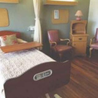 A hospital room with a patient bed and medical furniture.
