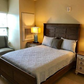 A cozy bedroom with a neatly made bed, nightstands, and a lamp.