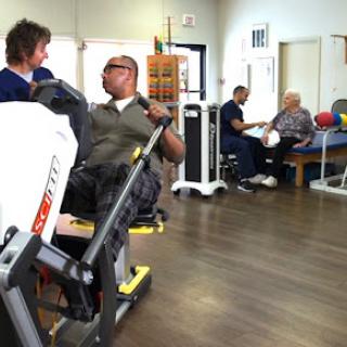 A scene from a rehabilitation center where patients are engaged in therapy activities with the assistance of healthcare professionals.