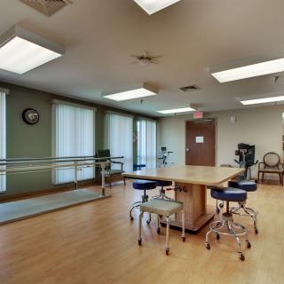 A rehabilitation room equipped with parallel bars and stools for physical therapy sessions.