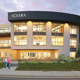 A modern office building with large windows, illuminated at night.