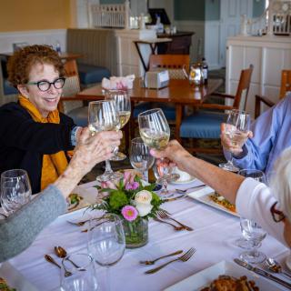A group of friends toasting with wine glasses around a beautifully set table in a restaurant.