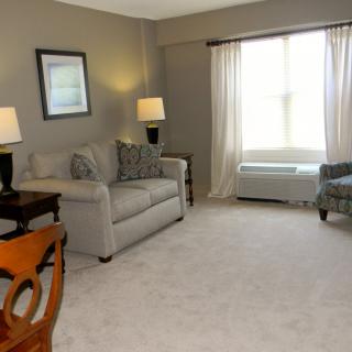 A cozy living room with a sofa, lamps, and a large window with curtains.