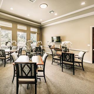 A modern dining area with neatly arranged tables and chairs, adorned with neutral decor and ample natural light.