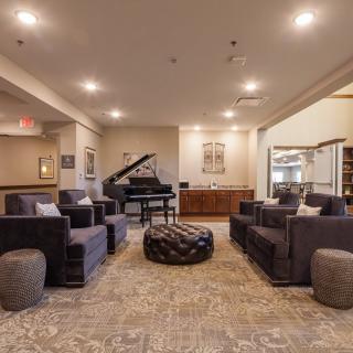 A modern lounge area featuring a grand piano and comfortable seating.