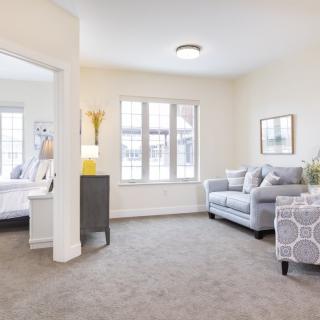 A bright and modern living room featuring a comfortable sofa, patterned armchair, and large window providing natural light.
