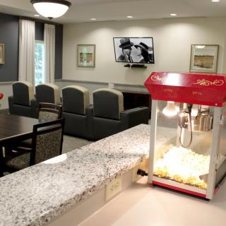 A cozy living room setup with a popcorn machine on the kitchen counter.