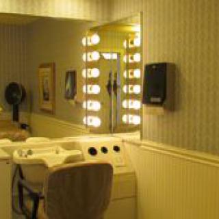A well-lit dressing room with a mirror and chair.