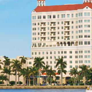 A waterfront hotel surrounded by palm trees under a clear blue sky.