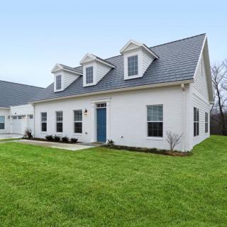 A modern white house with a well-maintained lawn and paved walkway.