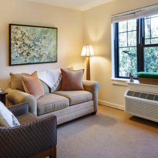A cozy living room with a sofa, armchair, and artwork on the wall.