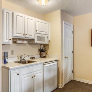 A compact kitchen area with white cabinets and a microwave.