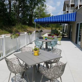 An outdoor patio with modern furniture and a blue-striped awning on a sunny day.