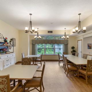 A well-lit dining room with several tables, chairs, and decorative chandeliers.